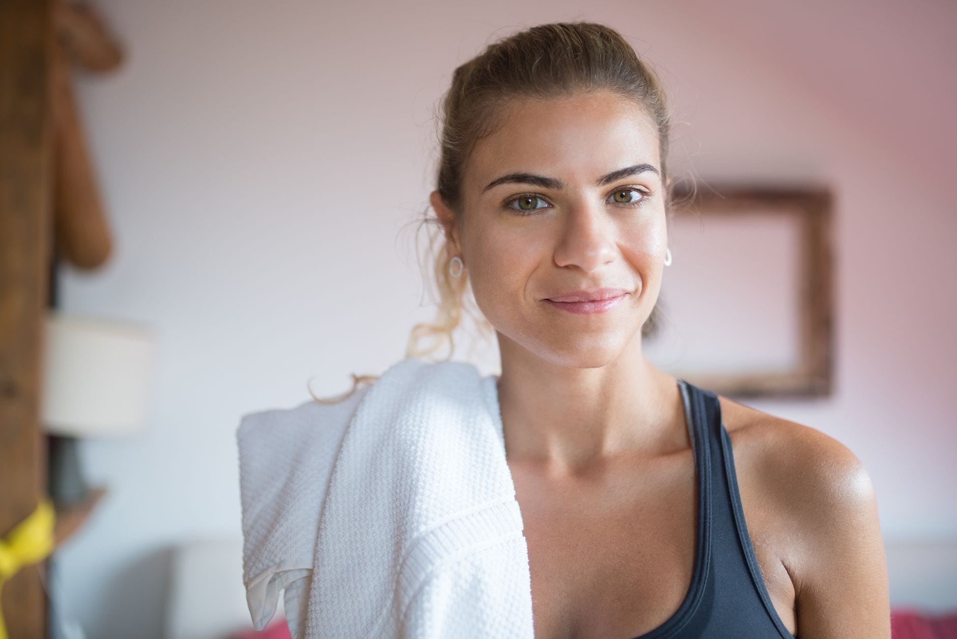 Uśmiechnięta kobieta z ręcznikiem po treningu w klubie fitness