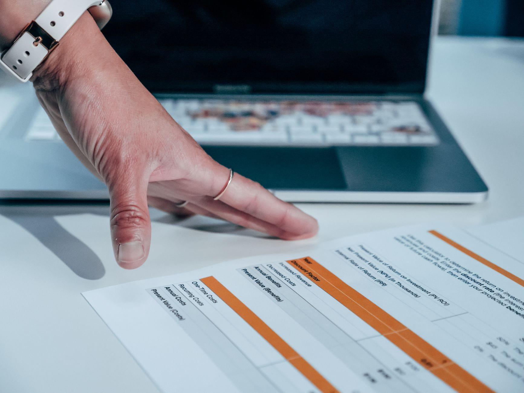 Jak tworzyć miesięczne raporty zarządcze w Google Sheets bez powtarzania pracy Dłoń analizująca raport finansowy na laptopie w Google Sheets